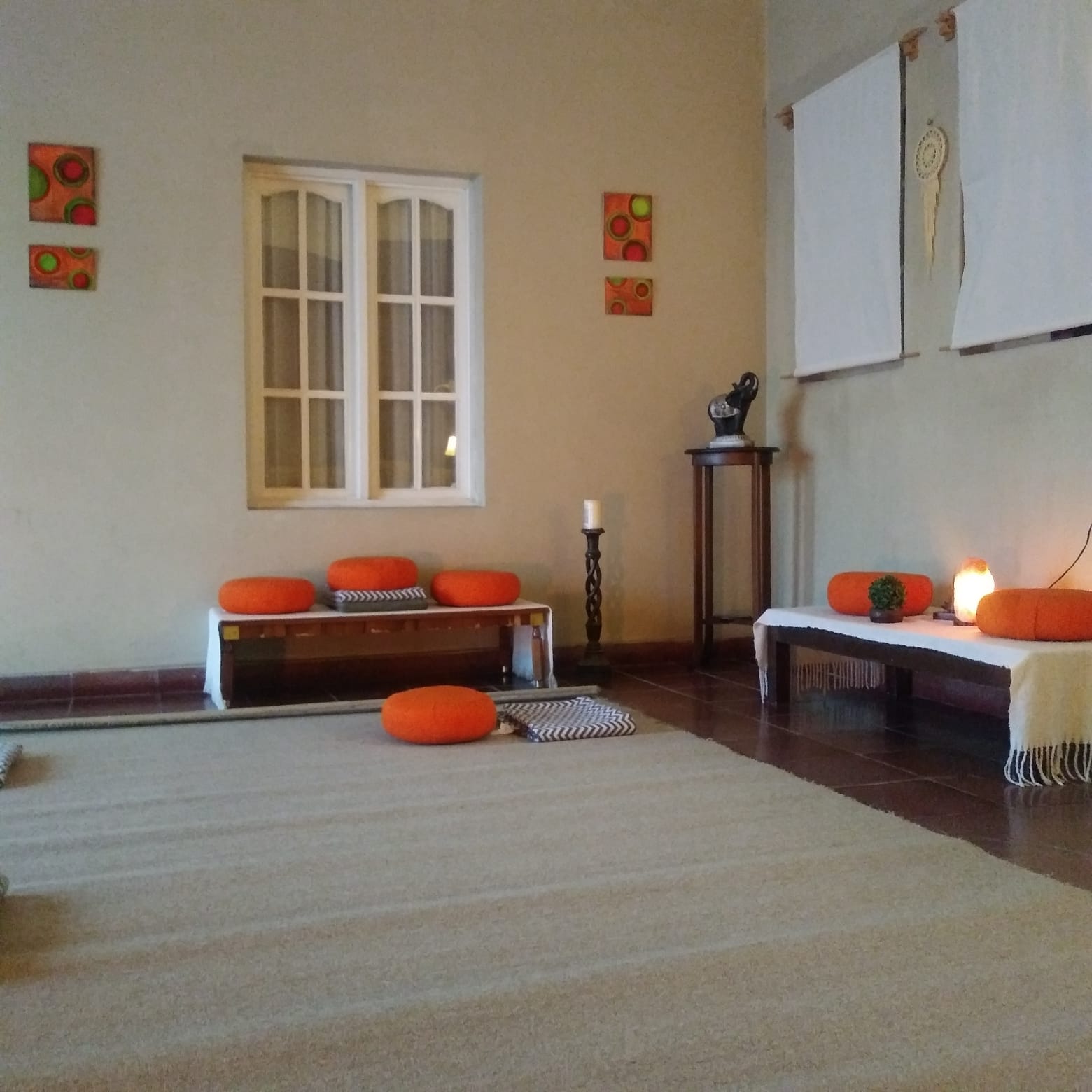 El salón de talleres, con almohadones naranjas y luz cálida